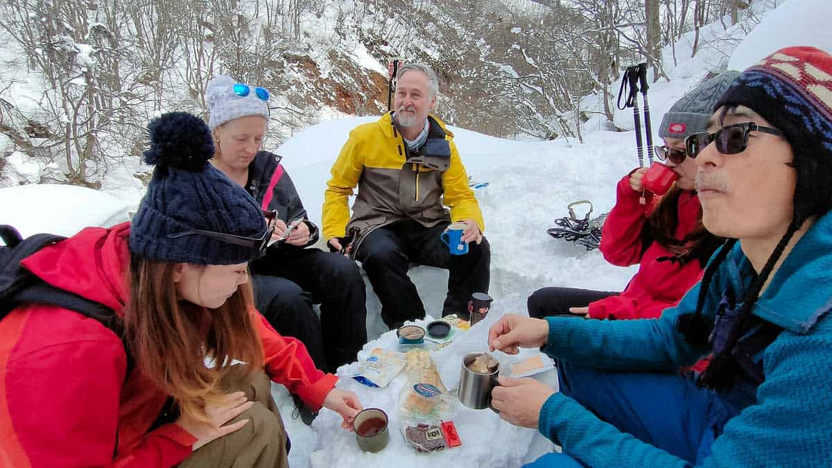 group of people having snacks and coffee around a handmade snow table