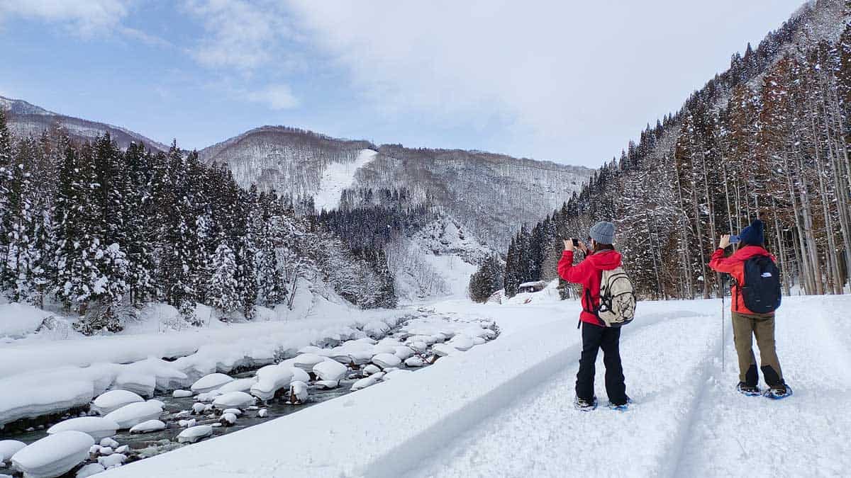 Two girls snowshoeing and taking a photo of the beautiful scenery