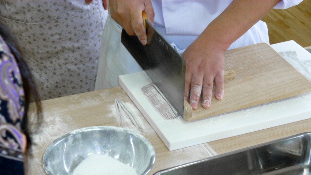 cutting soba noodles with a knife.